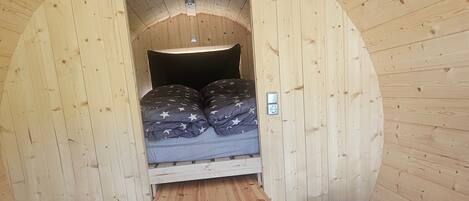 A wooden interior with a bed, a table, and a bench.