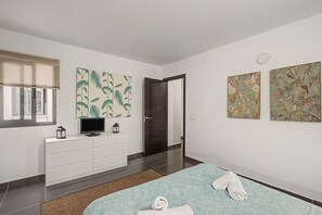 Une chambre à coucher moderne, avec un lit, une télévision, une commode et des œuvres d’art accrochées aux murs.