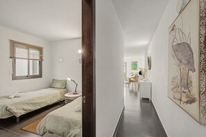 A modern bedroom with a bed, bedside table, and a window with blinds.