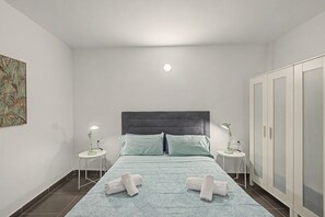 Une chambre à coucher avec un lit, deux tables de chevet, une armoire et un tableau accroché au mur.