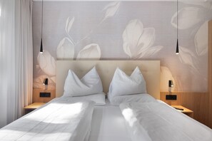 Ein Hotelzimmer mit einem großen Bett, zwei Nachttischen und einer Wand mit einem Blattmuster.