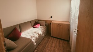 Ein kleiner, gemütlicher Raum mit einer Couch, einem Schrank und einer Tür.