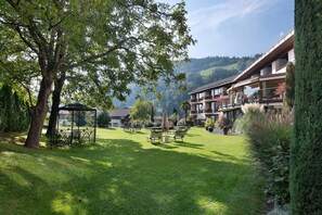 Ein Hotel mit Garten, Sitzgelegenheiten im Freien und Blick auf die Berge.