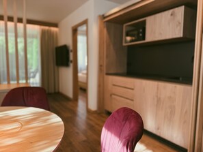 A modern kitchen with wooden cabinets and a microwave. There is a dining area with a round table and two chairs. - Apartment at Hotel and Residences Theresia with Mountain View and Private Terrace (St. Leonhard in Passeier)