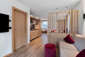 Ein modernes Interieur mit einer Küche, einer Sitzecke und einem an der Wand befestigten Fernseher.
