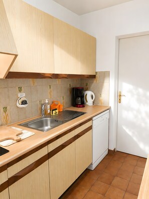 A kitchen with wooden cabinets, a stainless steel sink, a coffee maker, and a dishwasher.