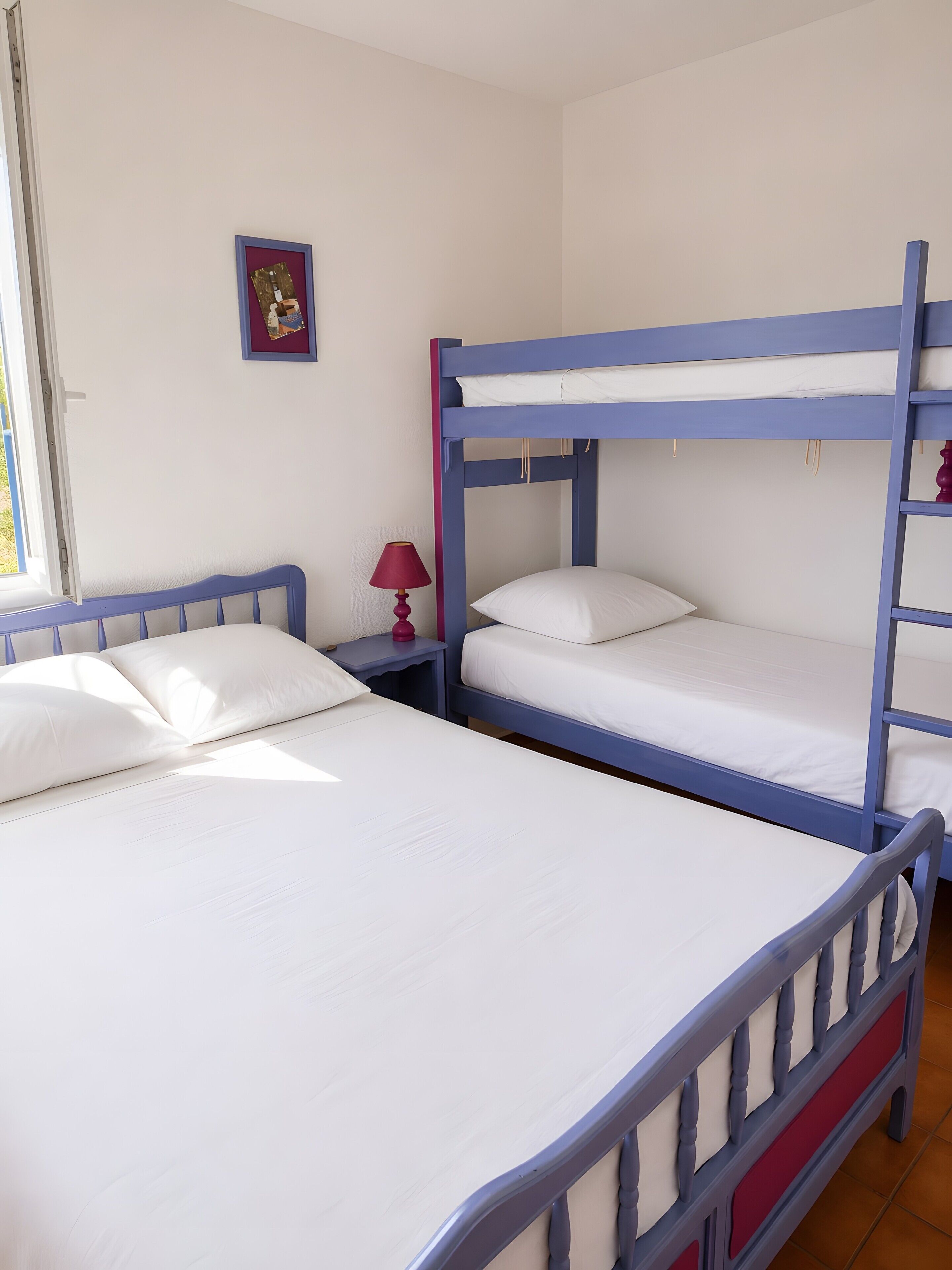Una camera con letti a castello, un comodino con una lampada e un piccolo quadro appeso al muro.