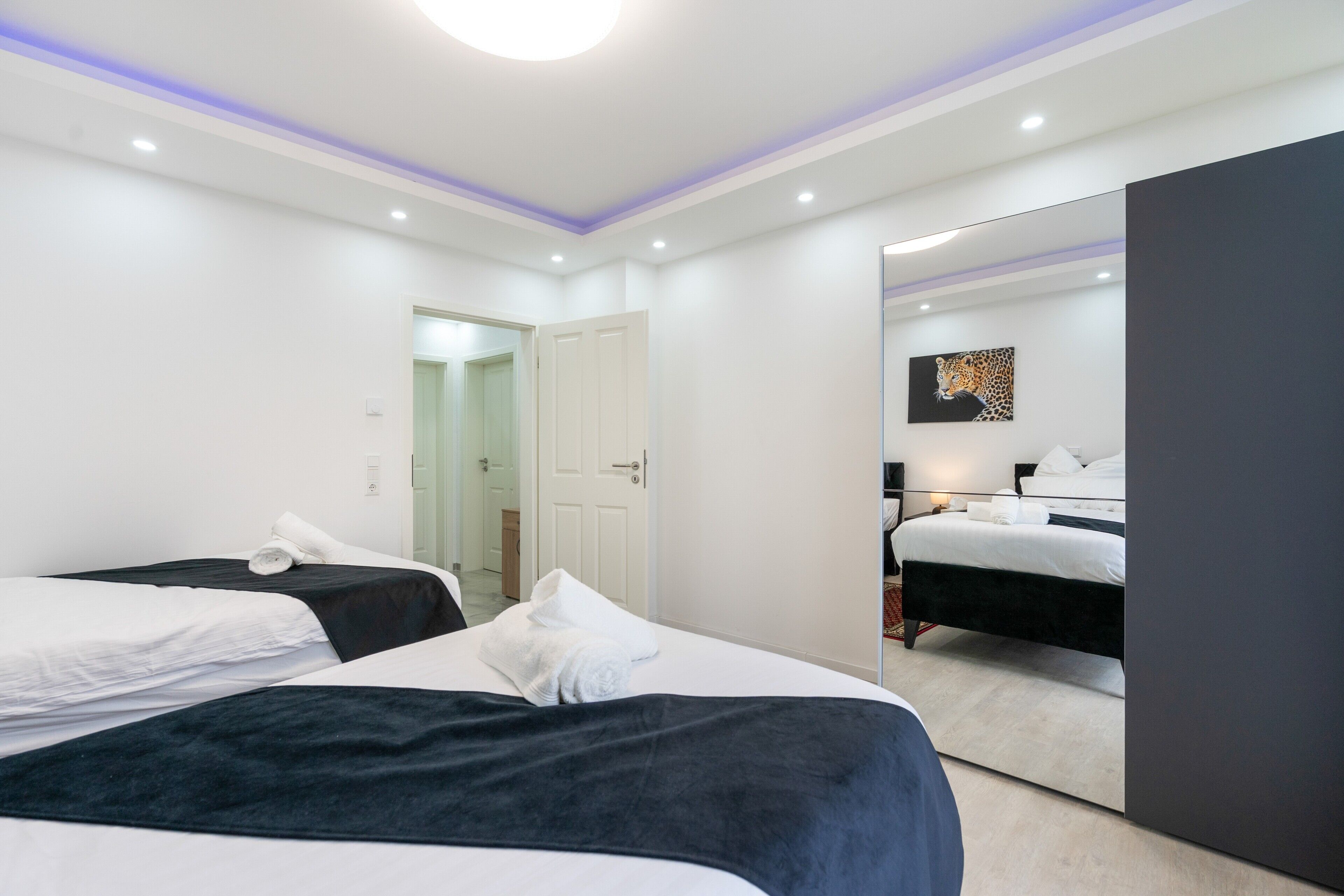 A hotel room with two beds, a large mirror, and a painting on the wall.