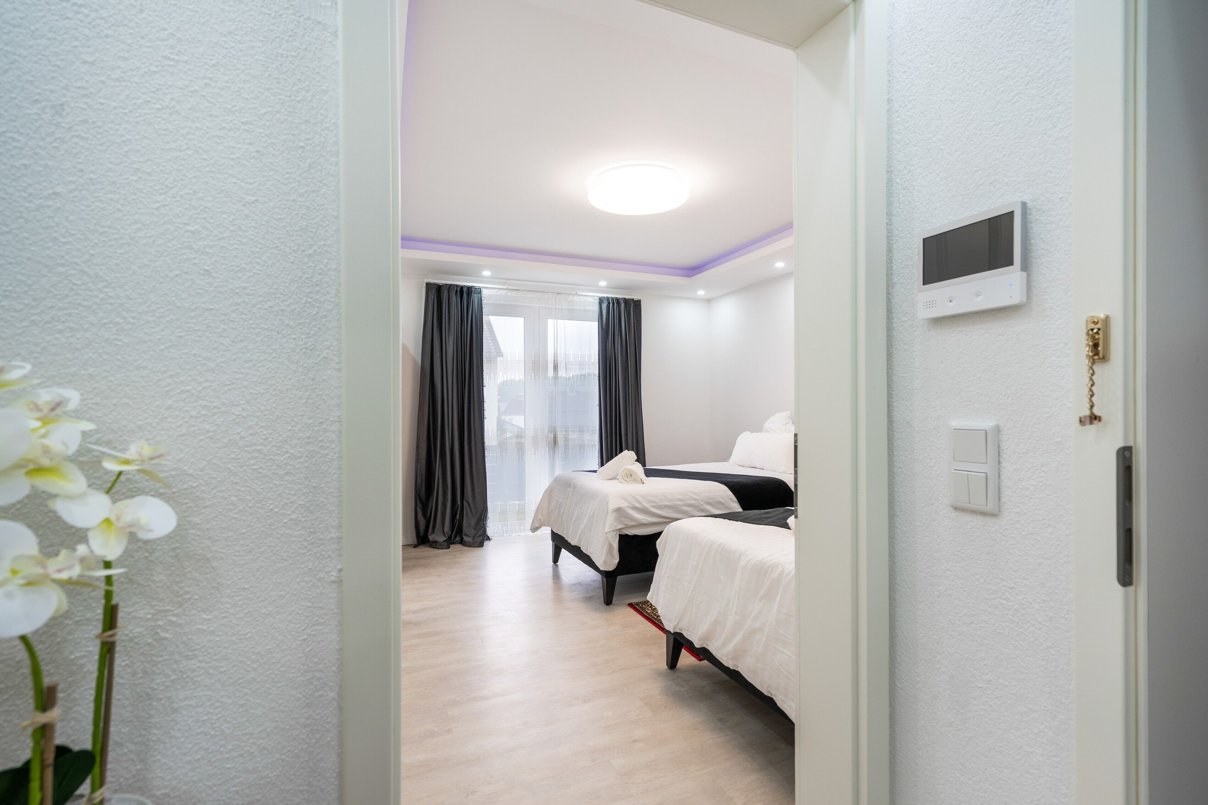 A hotel room with two beds, a TV, and a door with a lock.