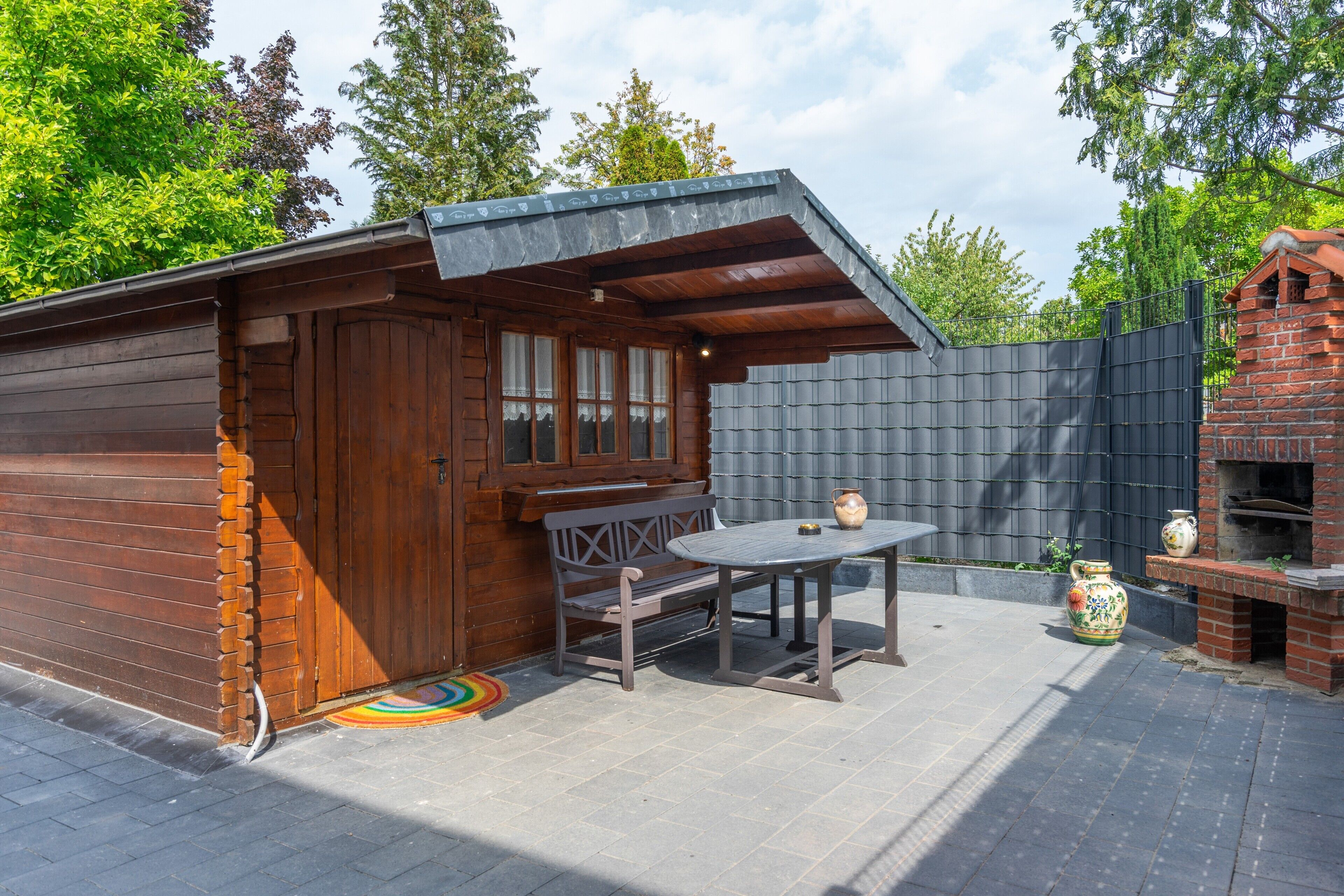 Eine Holzblockhütte mit Terrasse, Tisch und Grillplatz.