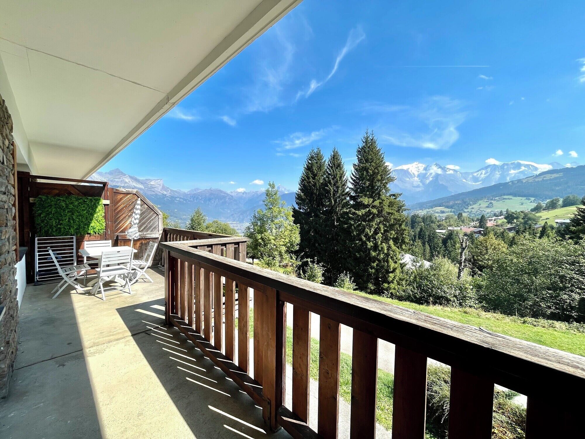 A balcony with a view of mountains and a wooden railing.