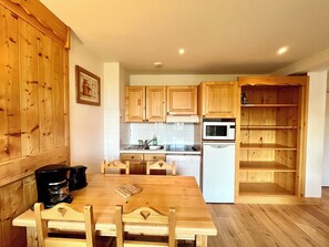 Una cucina compatta con mobili in legno, un frigorifero bianco, un forno a microonde e una macchina da caffè.