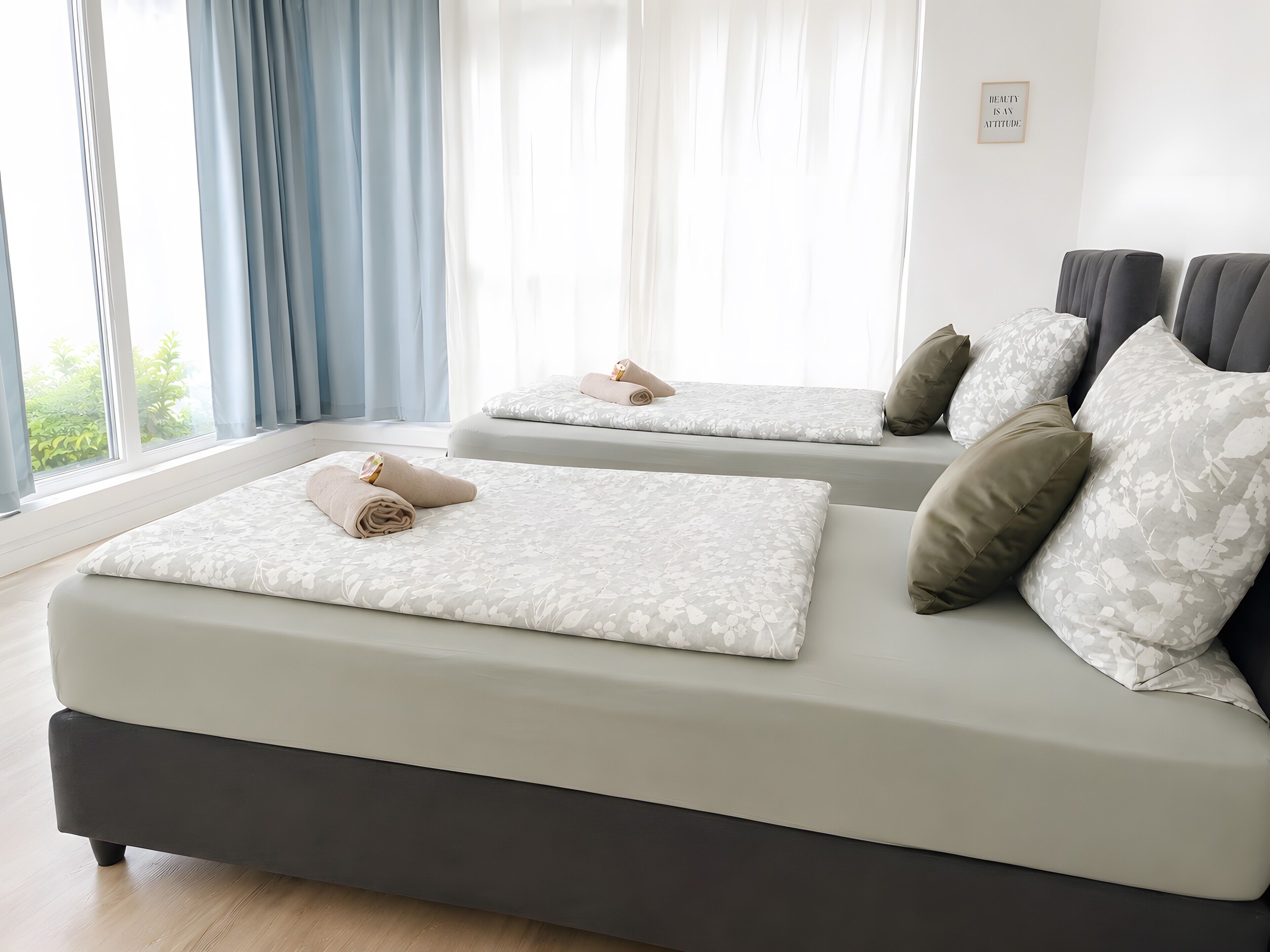 Een moderne slaapkamer met twee bedden, elk voorzien van een kussen en een opgerolde handdoek.