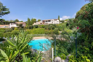 A swimming pool surrounded by lush greenery and a multi-story building in the background. - Apartment '2 Pièces Sainte Maxime' with Sea View, Shared Pool and Wi-Fi (Sainte-Maxime)
