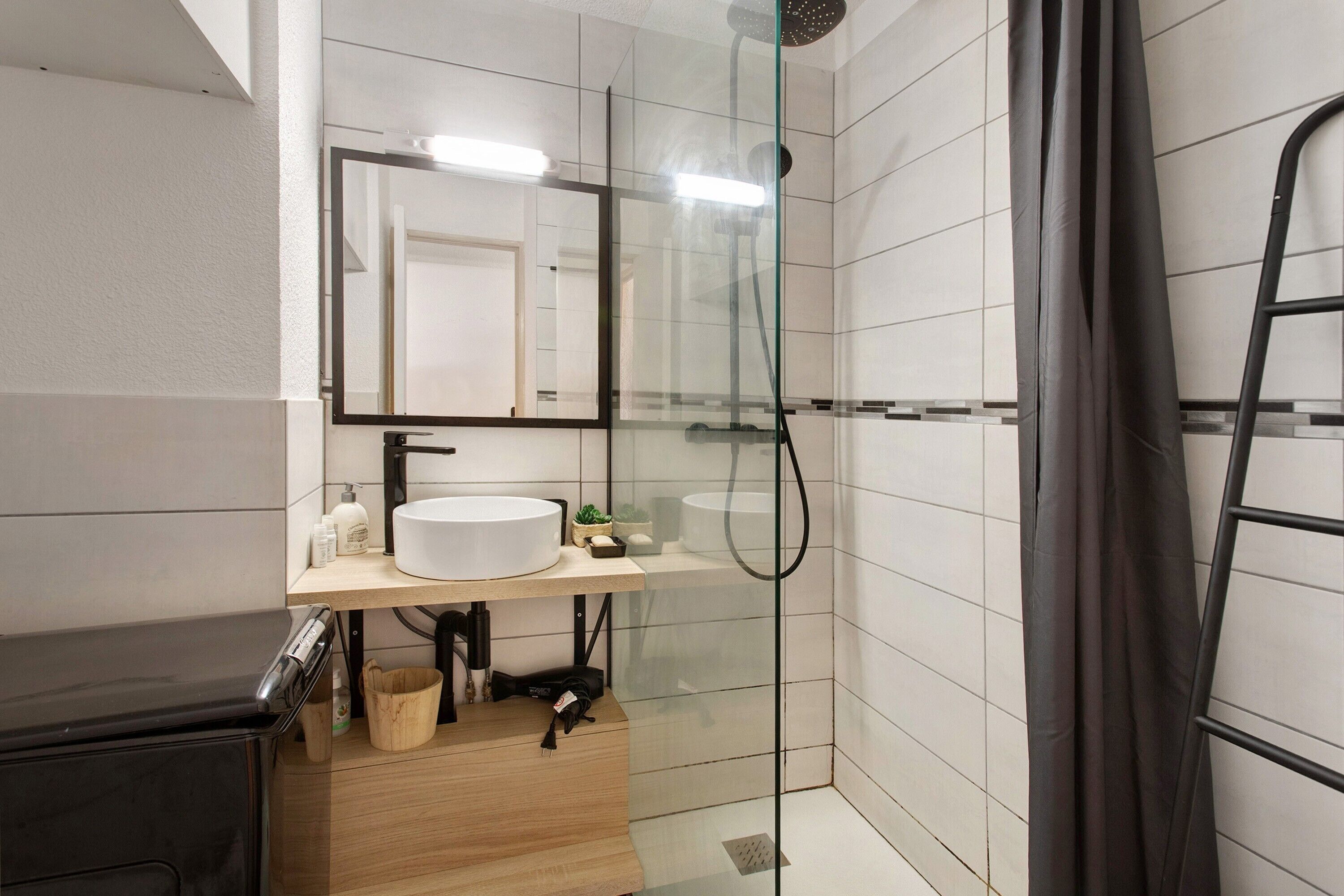 Une salle de bain moderne avec une douche à parois de verre, un meuble-lavabo en bois et un miroir au-dessus du lavabo.