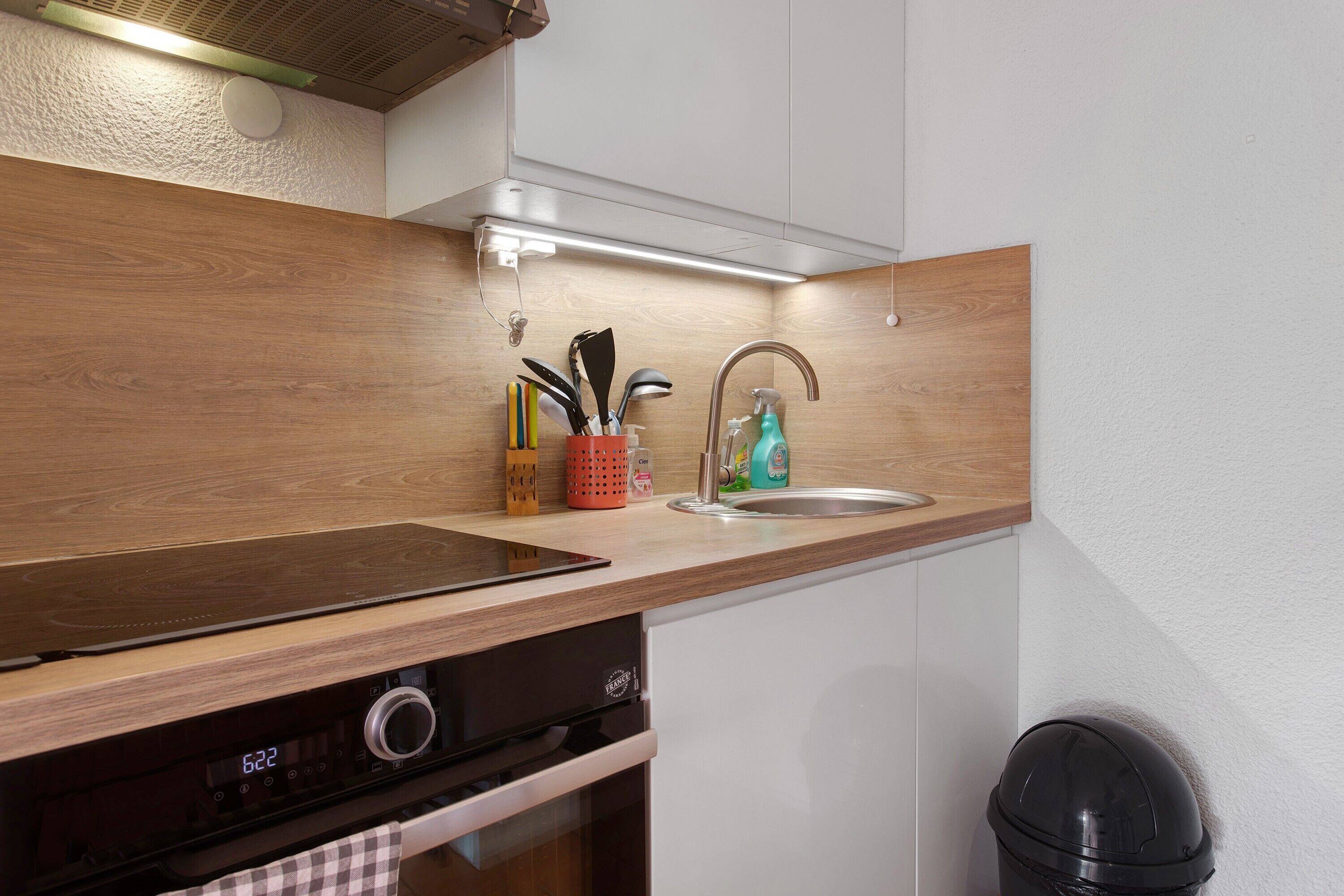 A kitchen with a wooden countertop, a stainless steel sink, and a dishwasher.