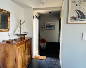 A hallway with a wooden cabinet, a sailboat model, a surfboard, and a framed picture on the wall.