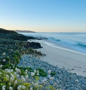 A coastal landscape with a rocky beach, waves, and a clear sky.