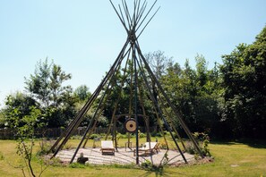 A traditional teepee structure with a circular platform and seating area.