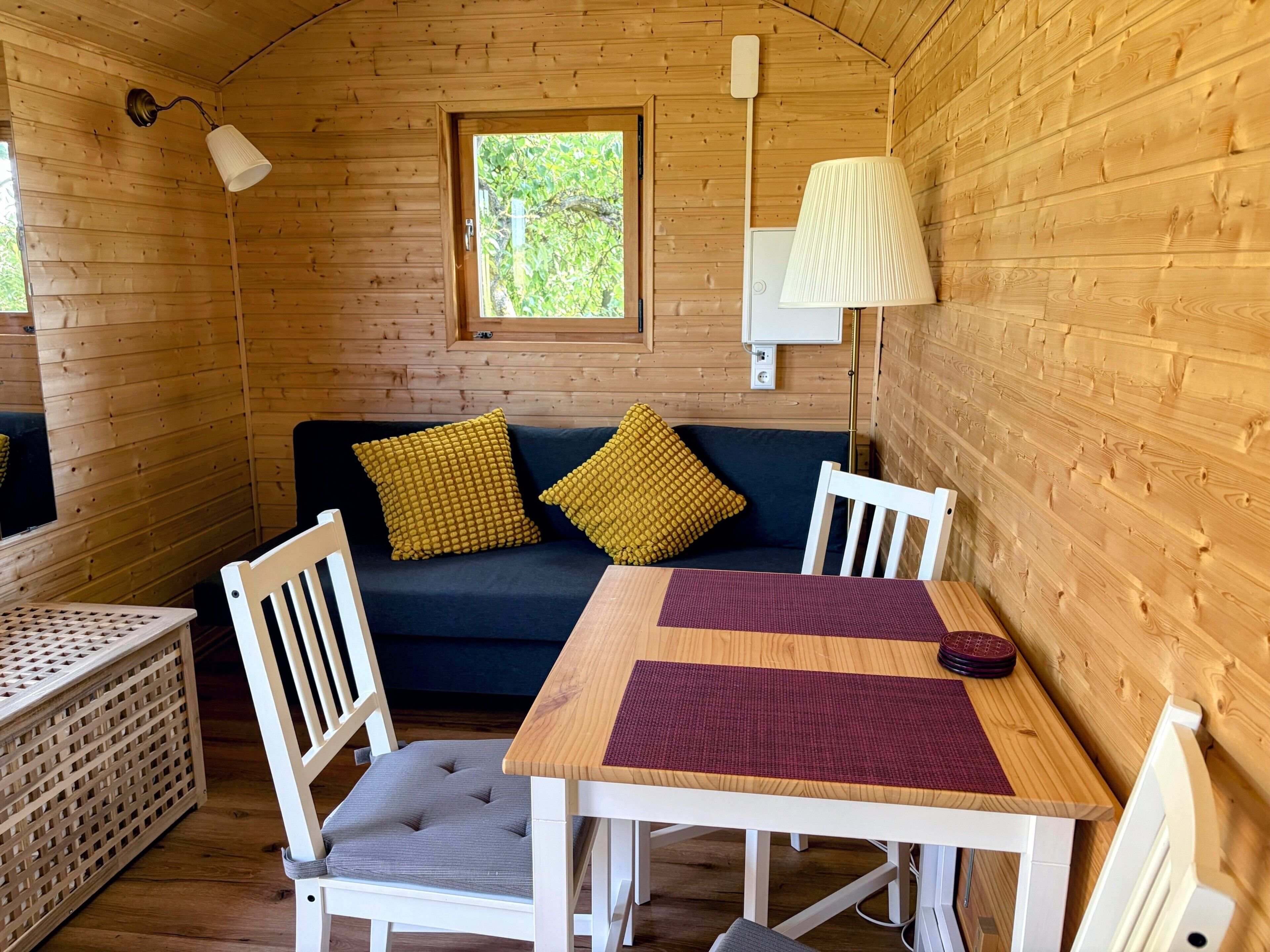 Ein gemütliches Blockhaus-Interieur mit Holzausstattung, einer Couch, zwei Sesseln, einem Tisch und einer Lampe.