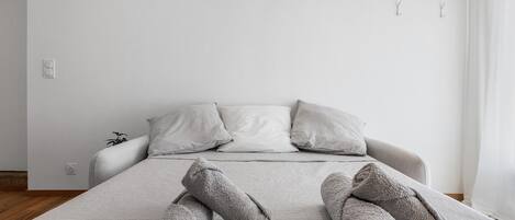 Een net opgemaakt bed met opgerolde handdoeken, een gestreept sprei en twee kussens.