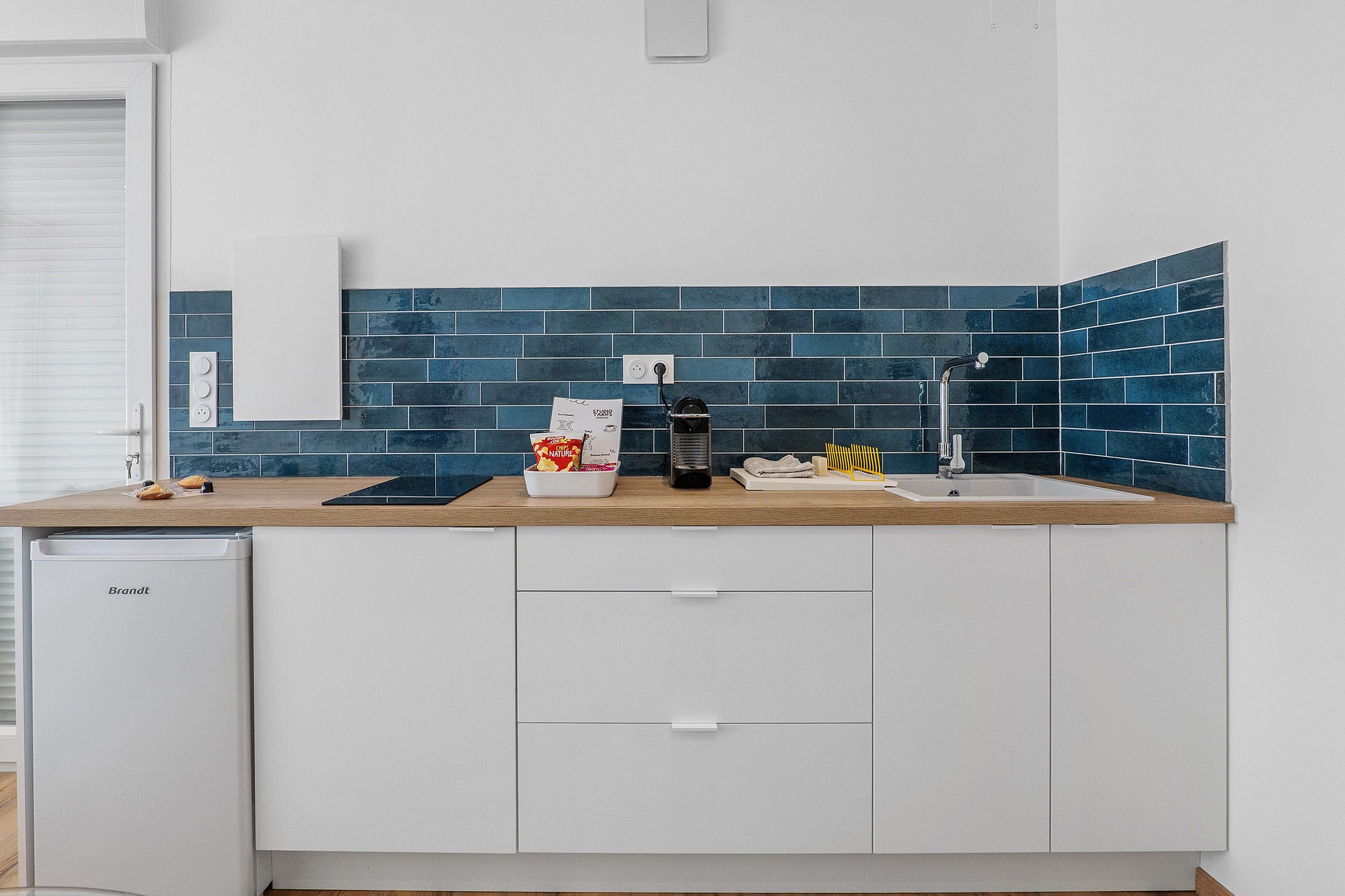 A modern kitchen with a built-in dishwasher, a sink, and a countertop with a blue-tiled backsplash.