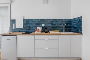A modern kitchen with a built-in dishwasher, a sink, and a countertop with a blue-tiled backsplash. - Fully Equipped Provence Studio with Mountain View, Wi-Fi, and Air Conditioning (Volonne)