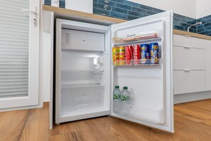 Et åbent køleskab med fryserum og en hylde med drikkevarer.