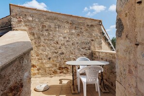 A stone wall with a small table and two chairs in a courtyard.