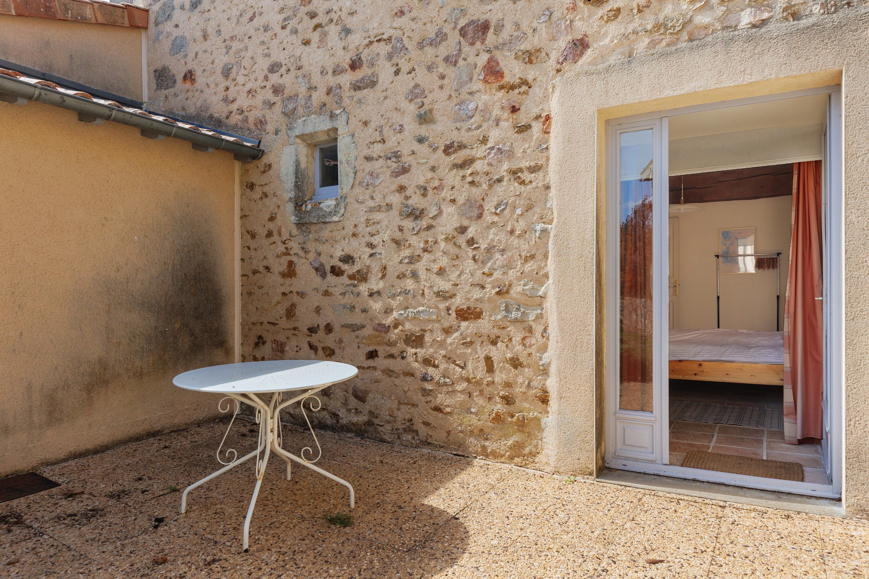 Un pequeño espacio al aire libre con una mesa y una puerta que da a un dormitorio.
