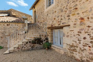 A stone building with a staircase leading to a window.