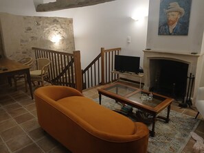 A living room with a sofa, a television, a fireplace, and a painting on the wall.