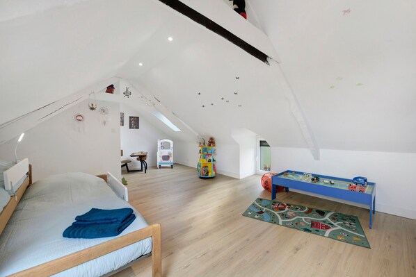 A child's bedroom with a lofted sleeping area, a play table, and various toys.