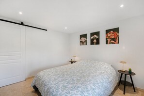A bedroom with a bed, a door, and three wall-mounted paintings.