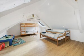 A children's room with two bunk beds, a play mat, and a toy truck set.