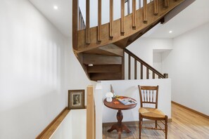 A wooden staircase with a white wall and a wooden floor.