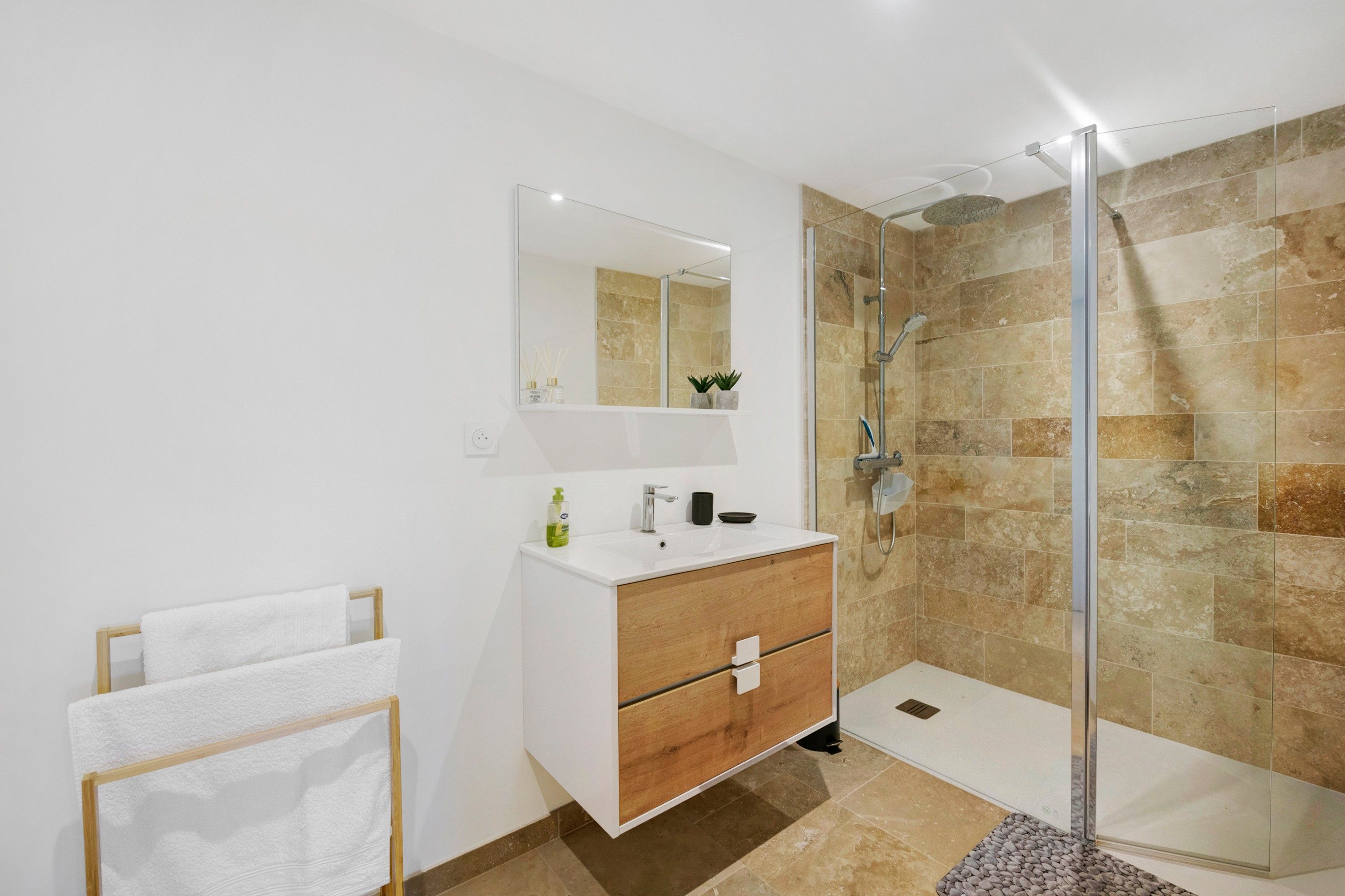 A modern bathroom with a glass shower enclosure, a white vanity with a mirror, and a towel rack.