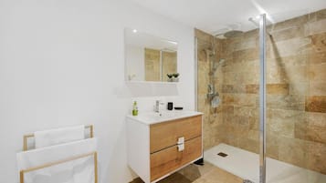 A modern bathroom with a glass shower enclosure, a white vanity with a mirror, and a towel rack.