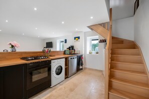 A modern kitchen with a central island, built-in oven, dishwasher, and washing machine.