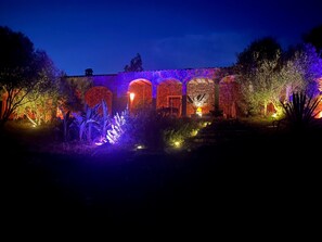 A building with multiple arched doorways, illuminated by warm and cool lighting, surrounded by lush vegetation. - The Olive Grove – Luxury Country Resort with Panoramic Views and Private SPA in Sardinia (Quartu Sant'Elena)
