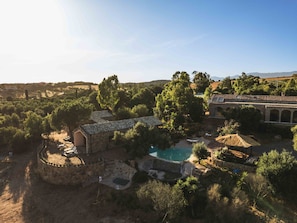 A villa with a swimming pool surrounded by trees and a stone wall. - The Olive Grove – Luxury Country Resort with Panoramic Views and Private SPA in Sardinia (Quartu Sant'Elena)