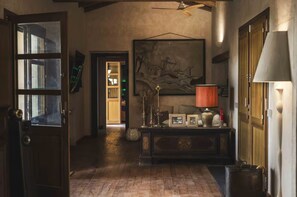 A hallway with a wooden floor, a large painting on the wall, a table with a lamp, and a door leading to another room. - The Olive Grove – Luxury Country Resort with Panoramic Views and Private SPA in Sardinia (Quartu Sant'Elena)