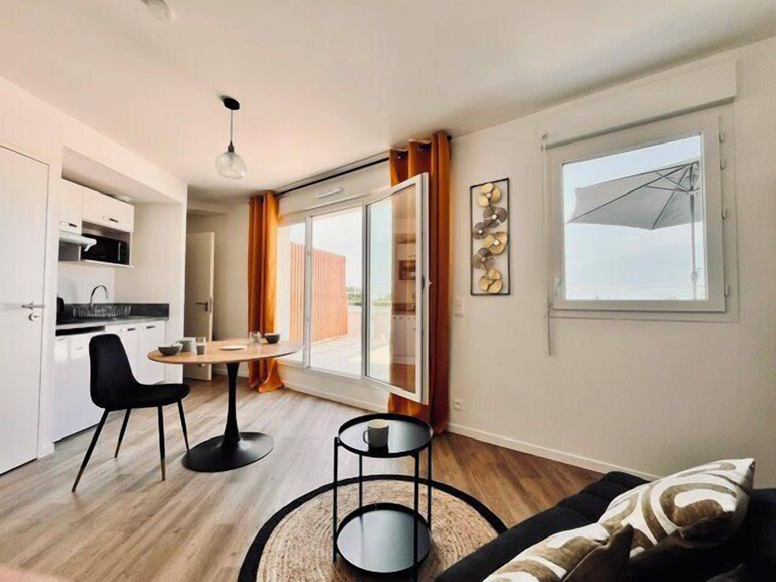 Ein modernes Wohnzimmer mit Essbereich, einer Couch, einem Couchtisch und Blick durch ein großes Fenster.