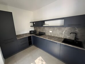 Eine moderne Küche mit dunklen Schränken, einer Marmor-Spritzschutzwand und einer schwarzen Arbeitsplatte.