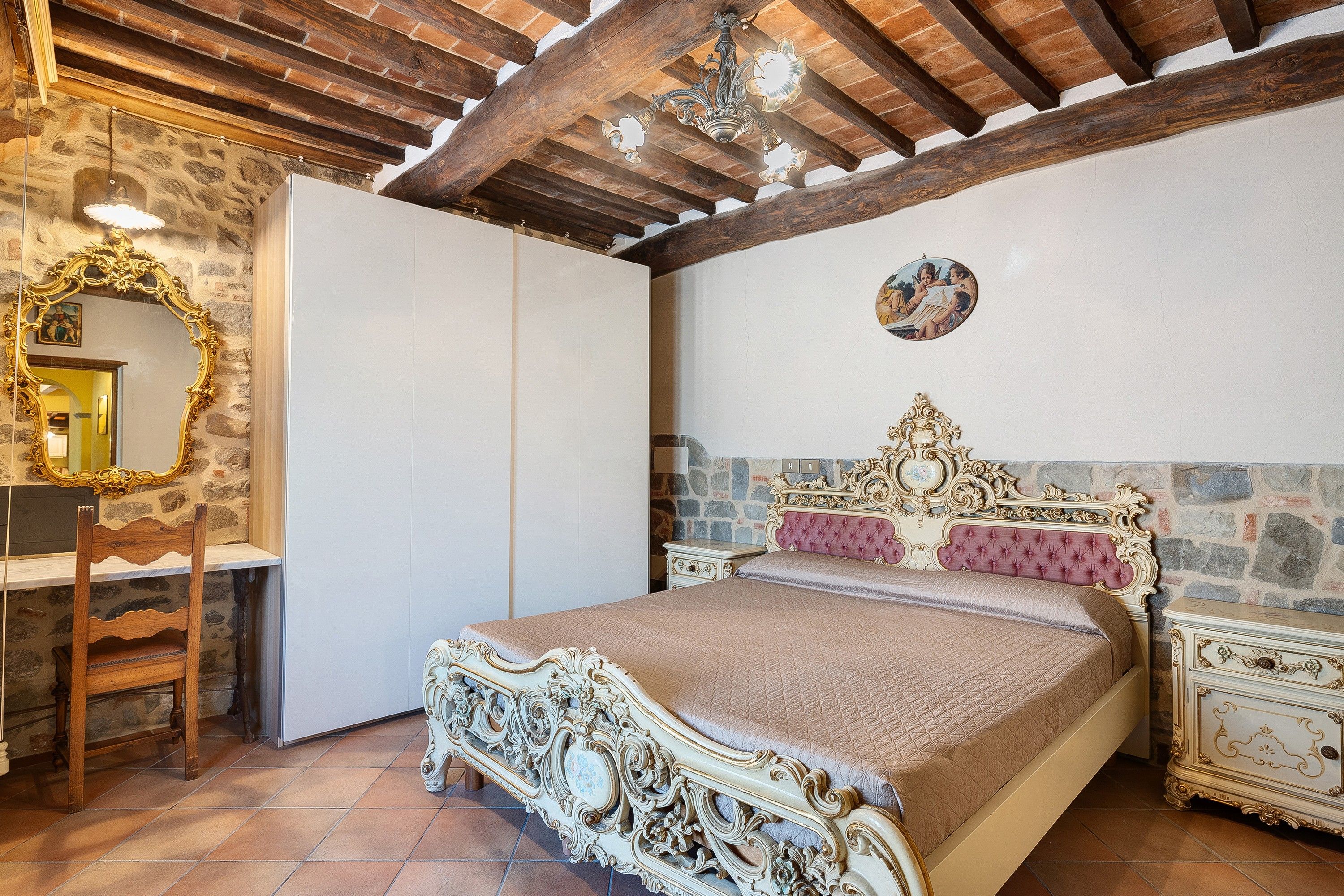 A bedroom with a large bed, a wardrobe, a mirror, and a chandelier.