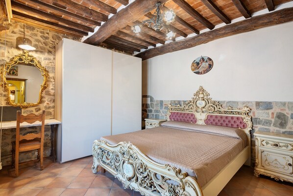 Un dormitorio con una cama grande, un armario, un espejo y una araña.