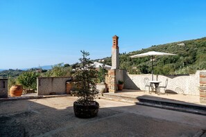 A rooftop terrace with a stone clock tower, potted plants, and a table with chairs. - Podere del Convento – House with Garden and Tuscan Views (Massa e Cozzile)