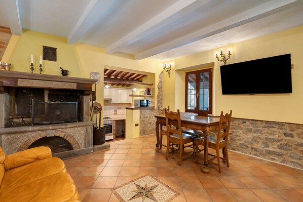 A dining area with a stone wall, a fireplace, and a television mounted on the wall.
