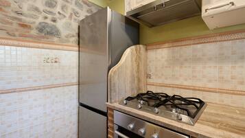 A kitchen with a stone wall, tiled backsplash, stainless steel appliances, and a gas stove.