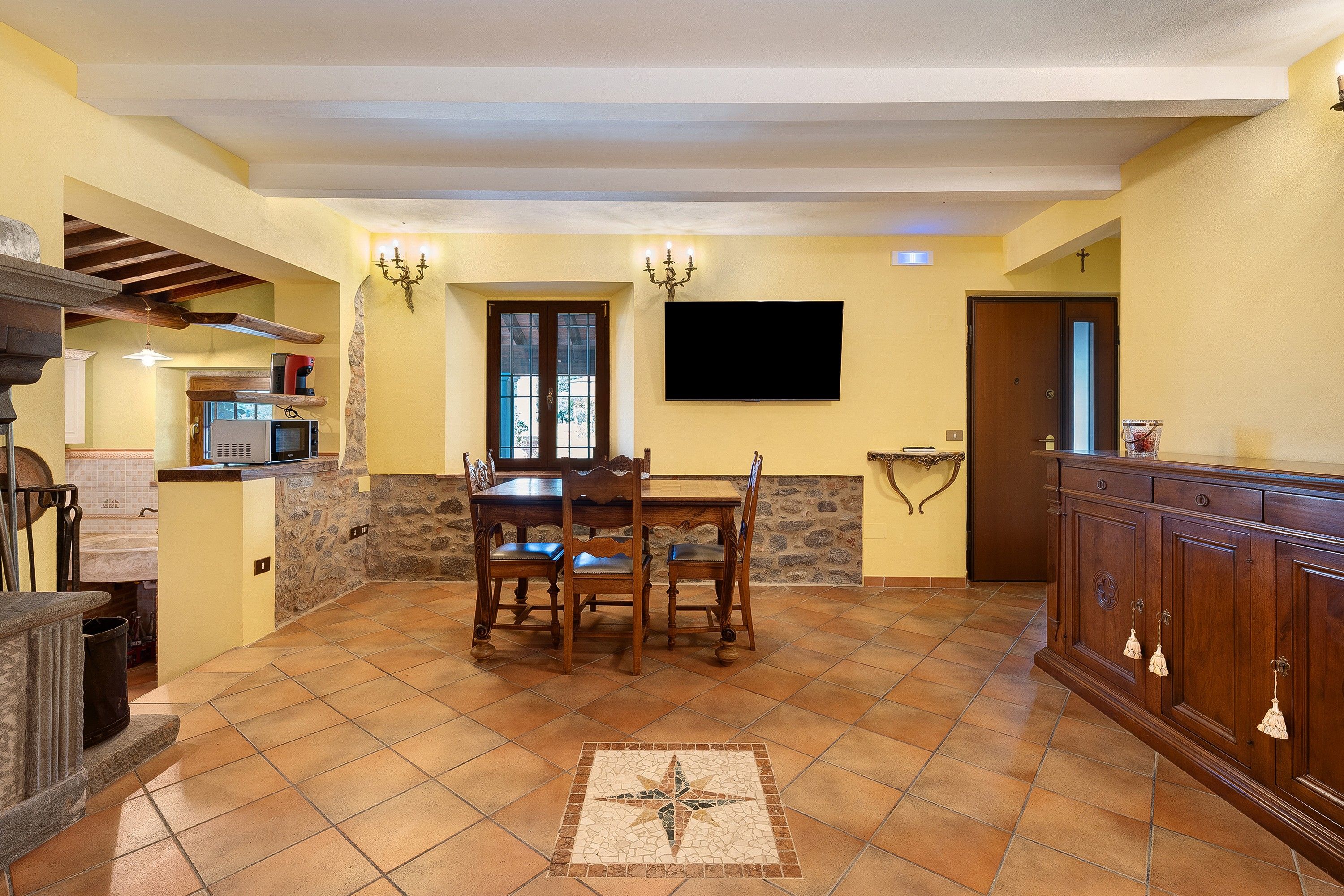 A spacious kitchen with a dining area, stone walls, and a tiled floor.